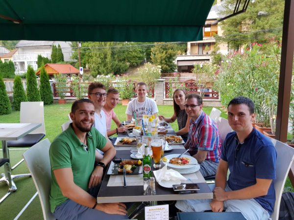 Smiling people sitting at a dinner table on a terrace.