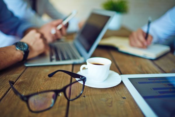 Tasse Kaffee und Brille im Büro-Arbeitsumfeld