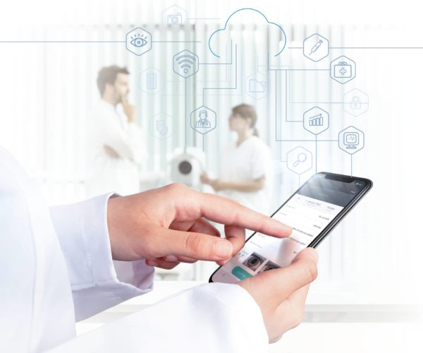 Doctor uses cloud-based medical application on smartphone, healthcare professionals talking in the background
